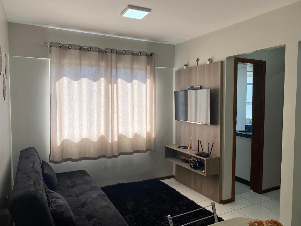 a living room with a couch and a television at Ap completo, confortável e bem localizado com vaga de garagem in Joinville