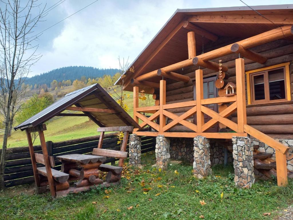 uma cabana de madeira com um banco à frente em Маєток У Ґазди em Synevyrsʼka Polyana