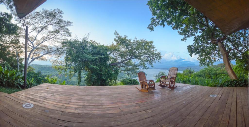 three people sitting on a wooden deck overlooking a lake at Casa 1800 Suchitoto Boutique in Suchitoto