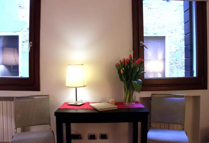 a table with a lamp and a vase of flowers on it at San Polo Feel The Center in Venice