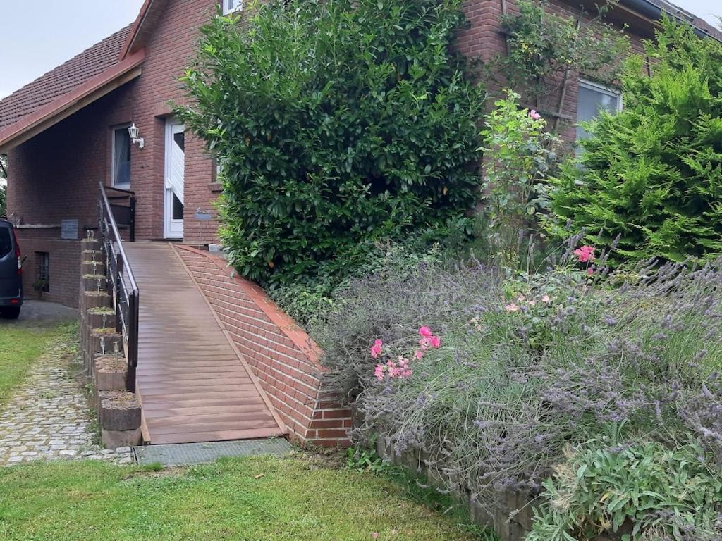 una pasarela de madera que conduce a una casa con plantas en Sonnige Ferienwohnung am Wald Büdnerreihe, en Heiligenhagen