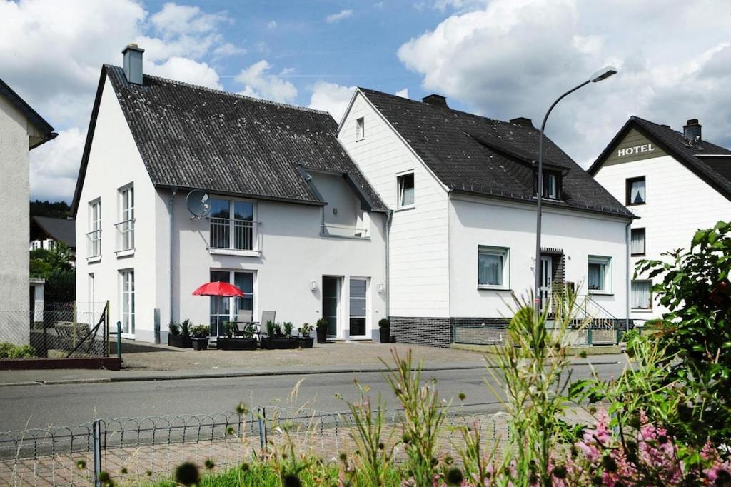 a white house with a black roof on a street at Apartment in Lissendorf with a paid private sauna in Lissendorf