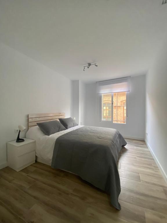 um quarto branco com uma cama e uma janela em Cozy flat in La Petxina_A em Valência