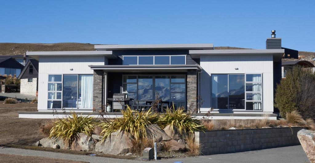 a house with large glass doors and windows at Lake Watch - Lake Tekapo in Lake Tekapo