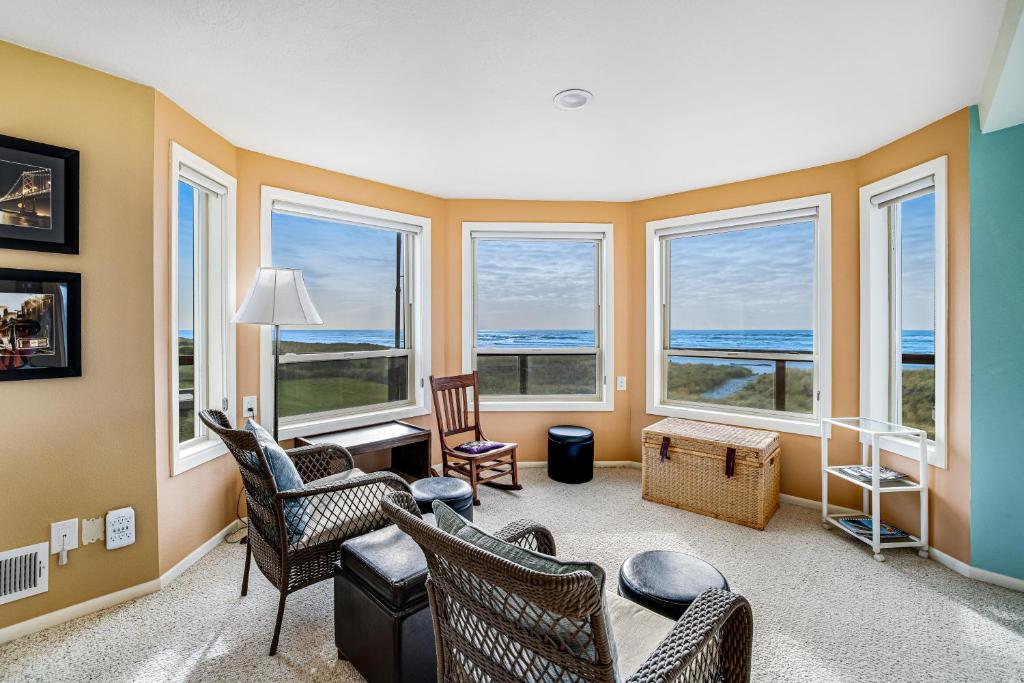 a living room with chairs and windows at Seabird Lodge in Rockaway Beach