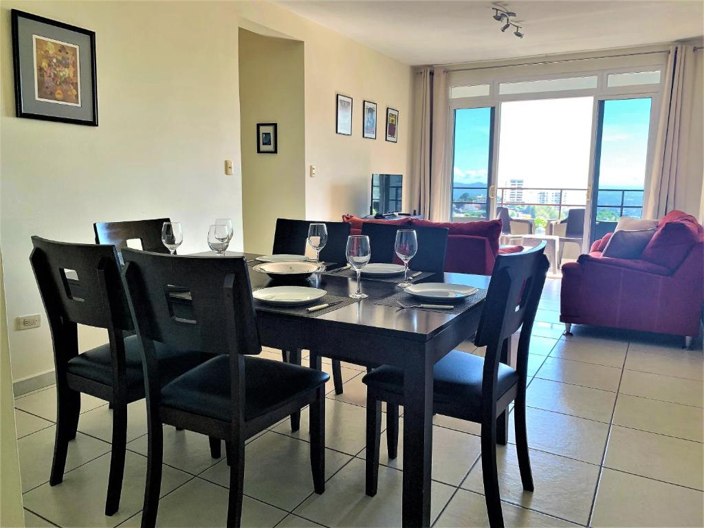 - une salle à manger avec une table, des chaises et des verres à vin dans l'établissement Luxury Modrn Apartment, w/amazing view, 3BR,Escalon,Exclus,Secur, à San Salvador
