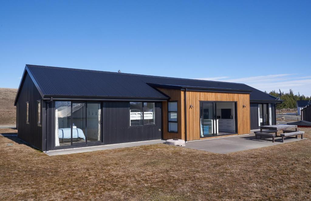 uma casa preta e de madeira num campo em Loudon Lodge - Lake Tekapo em Lake Tekapo