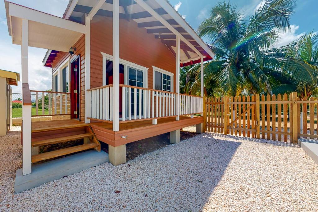 ein kleines Haus mit einer Veranda und einem Holzzaun in der Unterkunft Came at Hummingbird Estate Gold Standard Certified in Dangriga