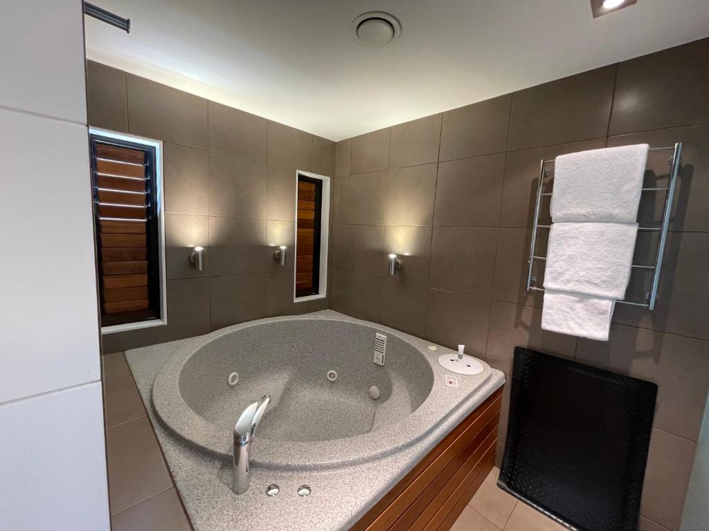 a bathroom with a large tub with a sink at Bentleys Motor Inn in Palmerston North