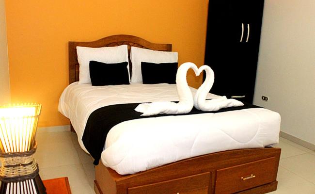 Un dormitorio con una cama con dos cisnes. en Hostal Universal Huaraz, en Huaraz