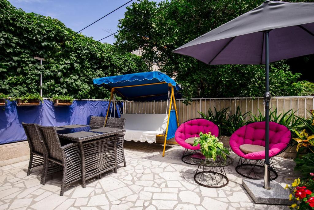 a patio with pink chairs and an umbrella at Rooms Edna in Dubrovnik