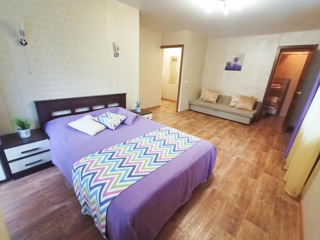 um quarto com uma cama roxa e um sofá em Apartments on Tolbukhina 64 em Yaroslavl