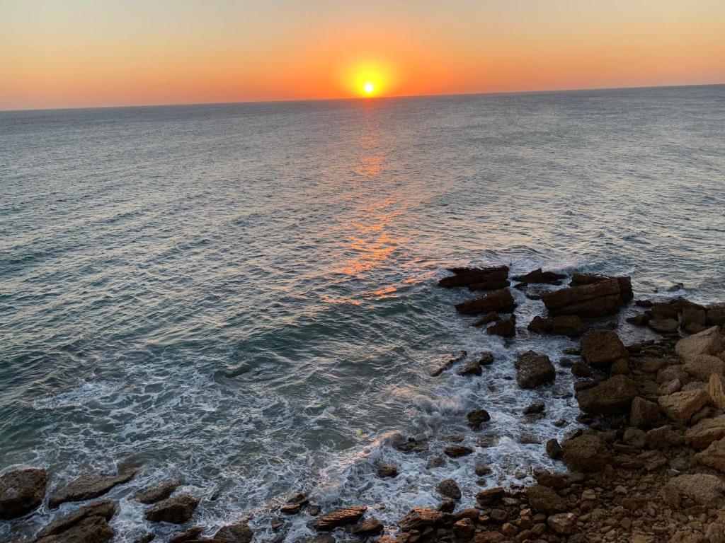 a sunset over the ocean with rocks in the water at Casa Anna in Conil de la Frontera