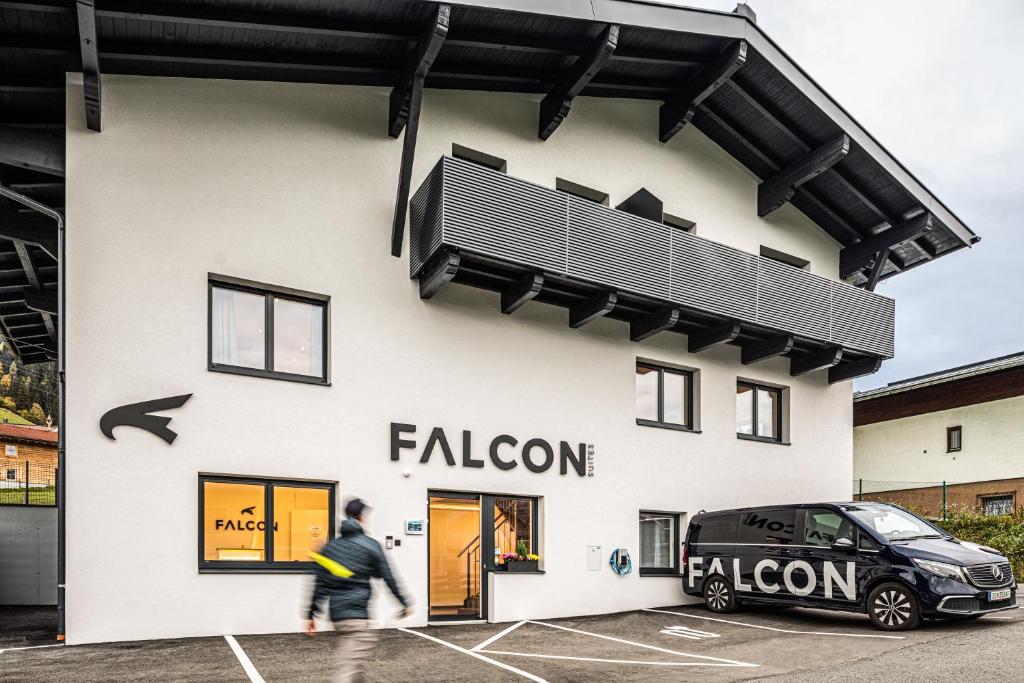 Falcon Suites Kaprun - Summercard included في كابرون: رجل يسير بجوار مبنى به سيارة متوقفة في الخارج