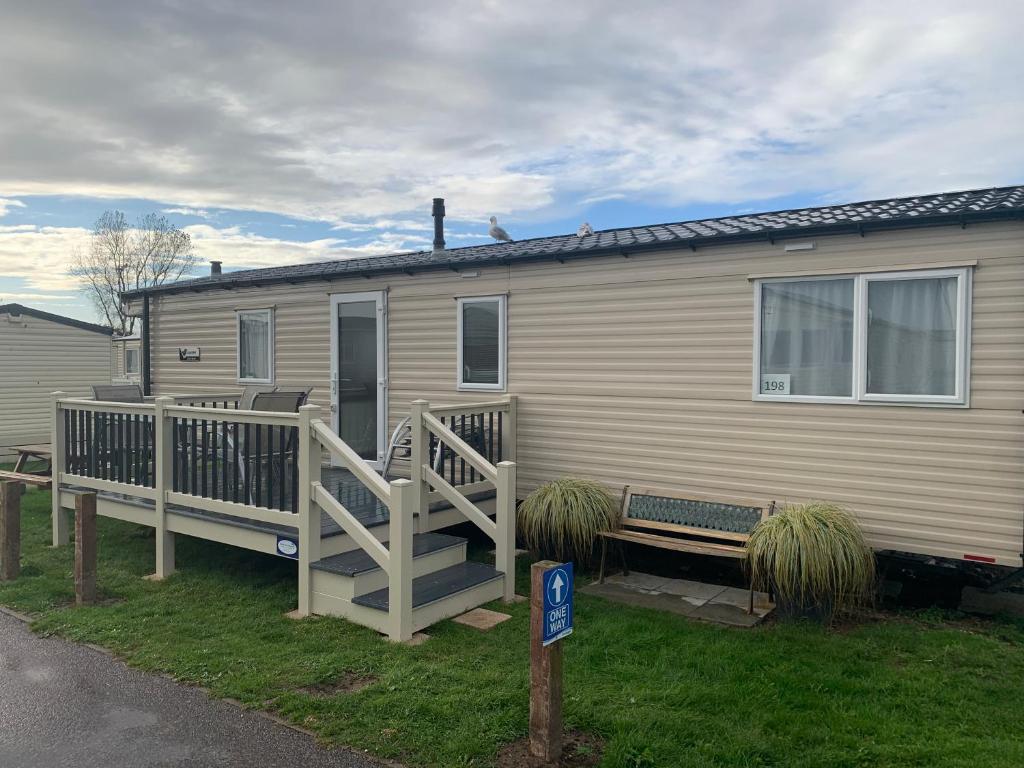 a mobile home with a porch and a deck at Gold Plus 6 Berth Caravan in NEW BEACH with parking WiFi and decking in Dymchurch