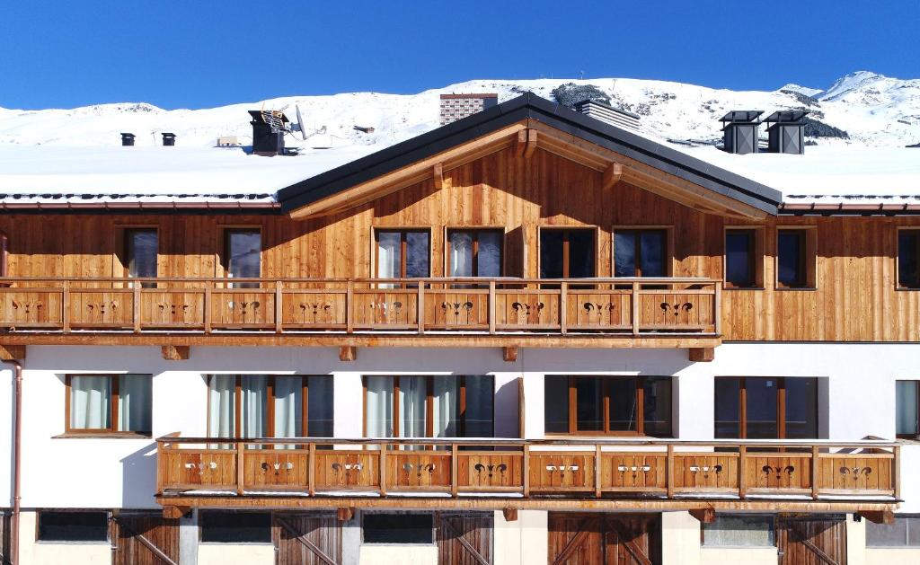 a large wooden building with snow on the roof at Odalys Chalet D&#39;Alice in Les Menuires