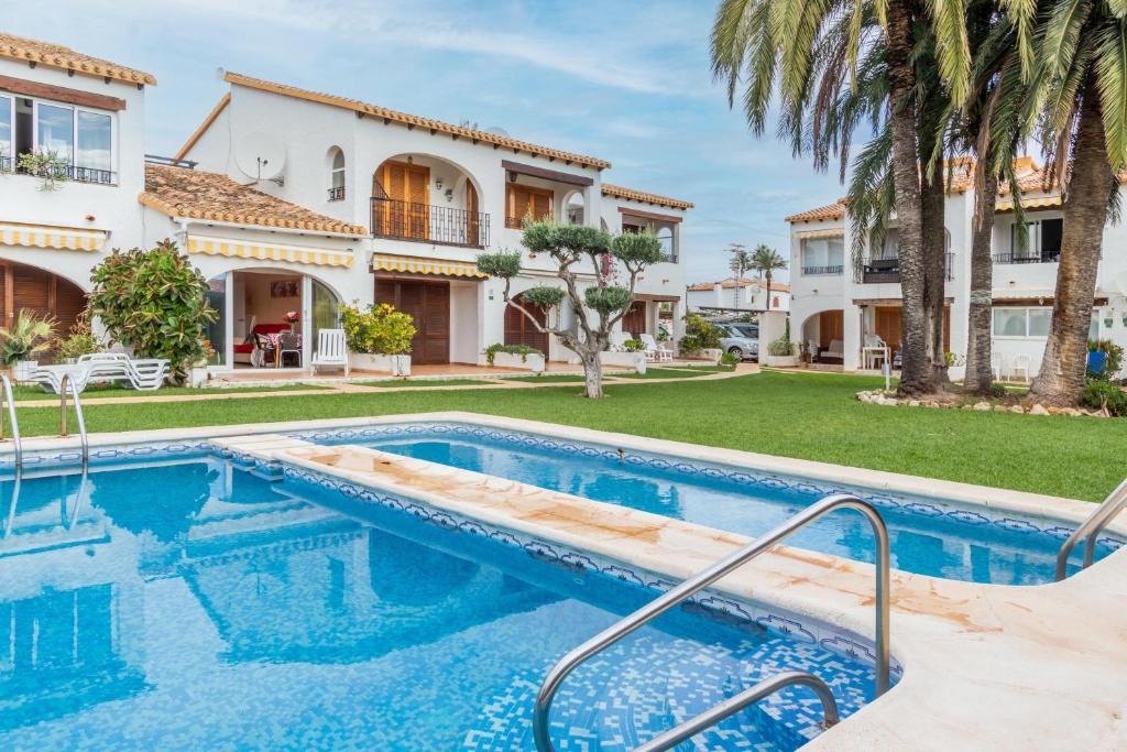una piscina frente a una casa con palmeras en Well equipped 1 Bedroom Bungalow, en Denia