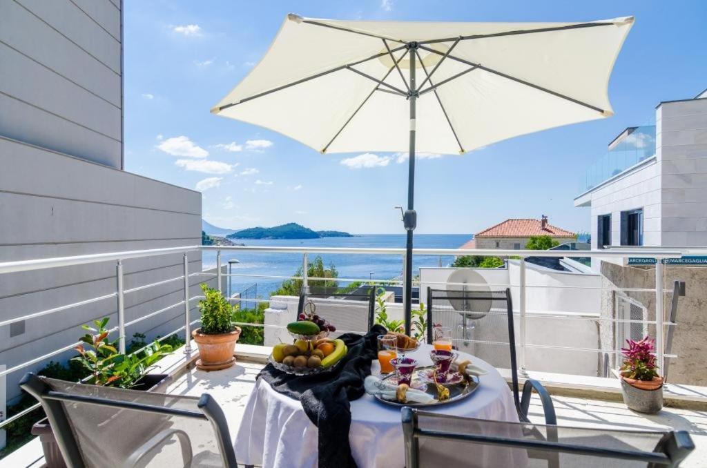 a table on a balcony with an umbrella at Apartment & Room Lady O in Dubrovnik