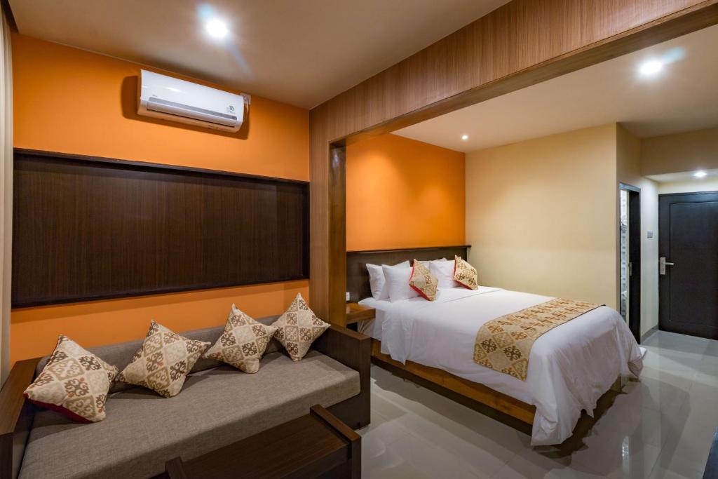 een hotelkamer met een bed en een bank bij AB Hotel Kuta in Kuta
