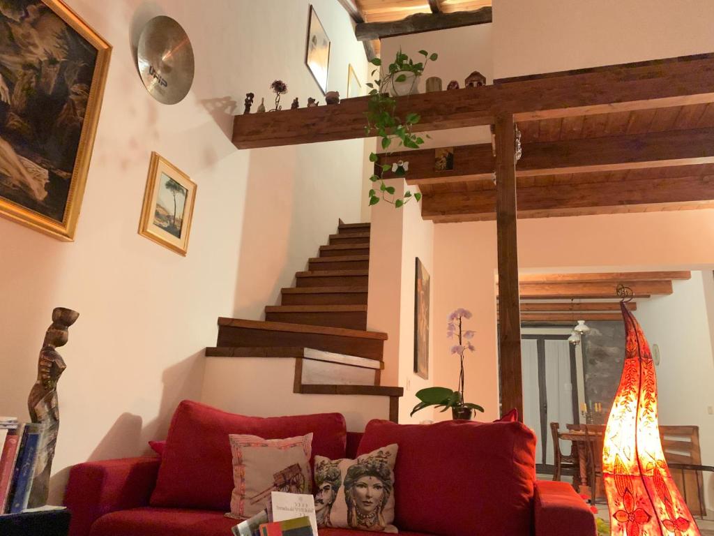 a living room with a red couch and stairs at Lisa's home Piedimonte Etneo in Piedimonte Etneo