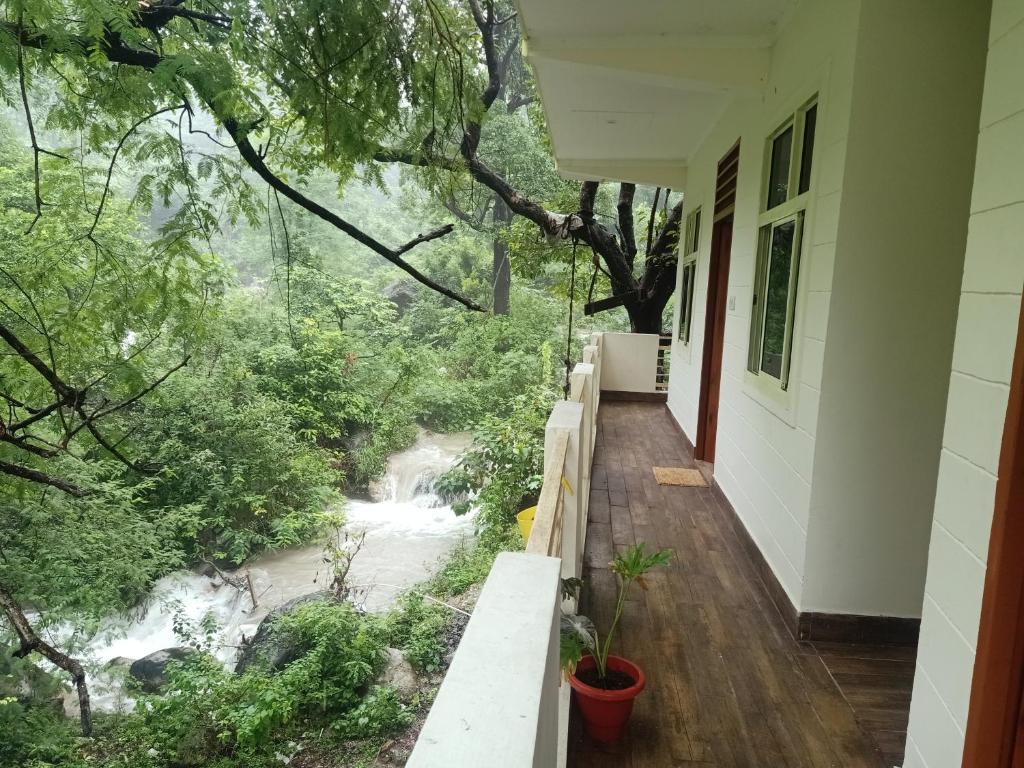 Cette maison possède un balcon offrant une vue sur la rivière. dans l'établissement Shivanjal Wellness and Accommodation, à Rishikesh