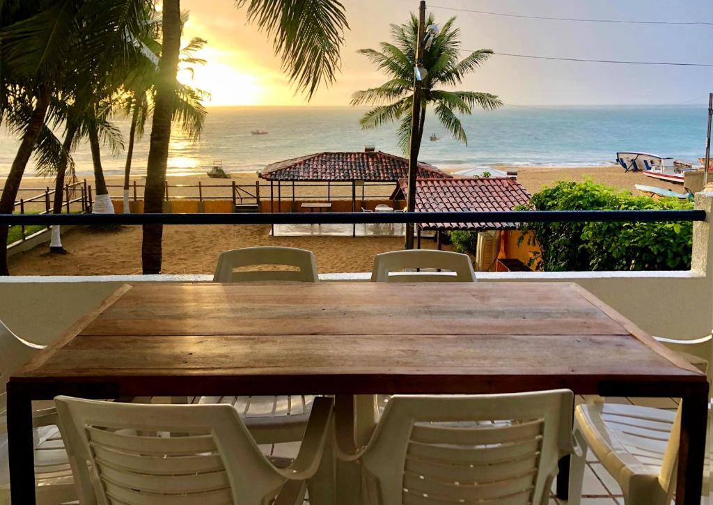 - une table et des chaises en bois avec vue sur la plage dans l'établissement Casa/Apto em Condomínio na Beira-Mar em Tamandaré / Próximo a Praia dos Carneiros, à Tamandaré