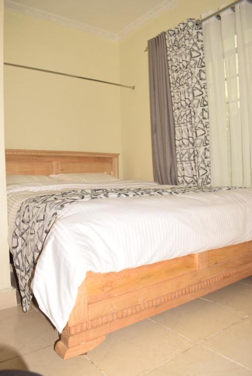 Un dormitorio con una cama grande con ventana. en Stylish 2BR with Wi-Fi and secure parking, en Kakamega