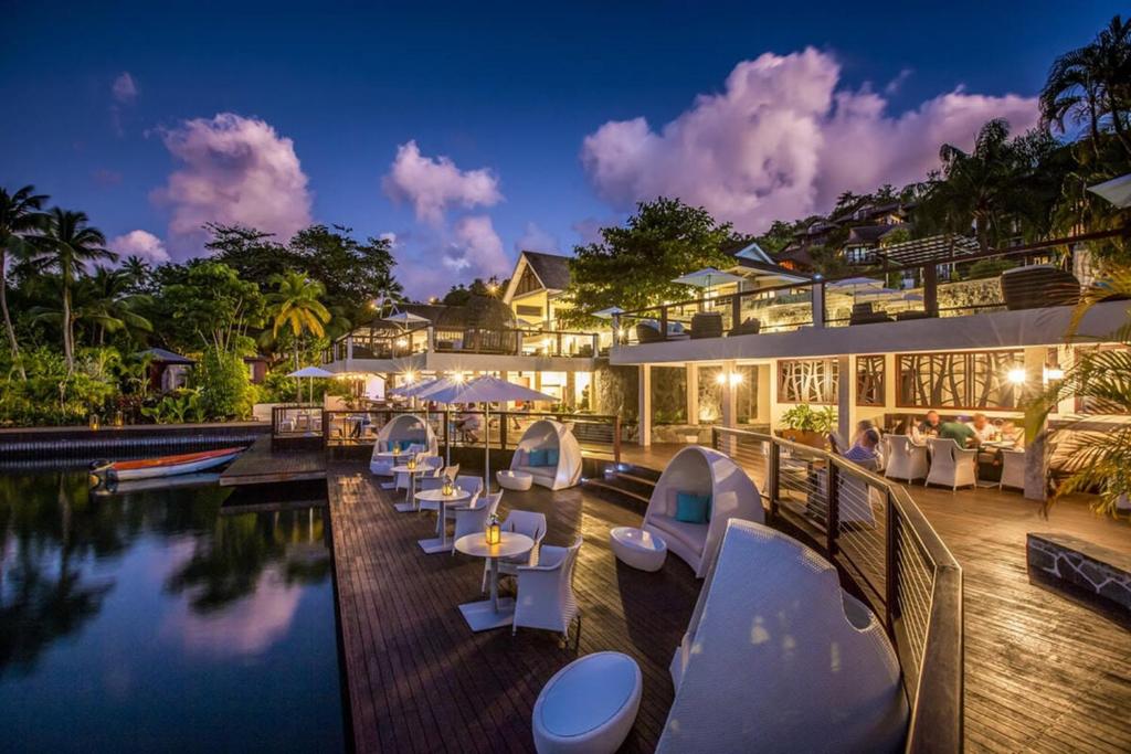 Un complejo con piscina, mesas y sillas. en Superb Split Level Waterside Apt, Marigot Bay, St Lucia WI, en Castries