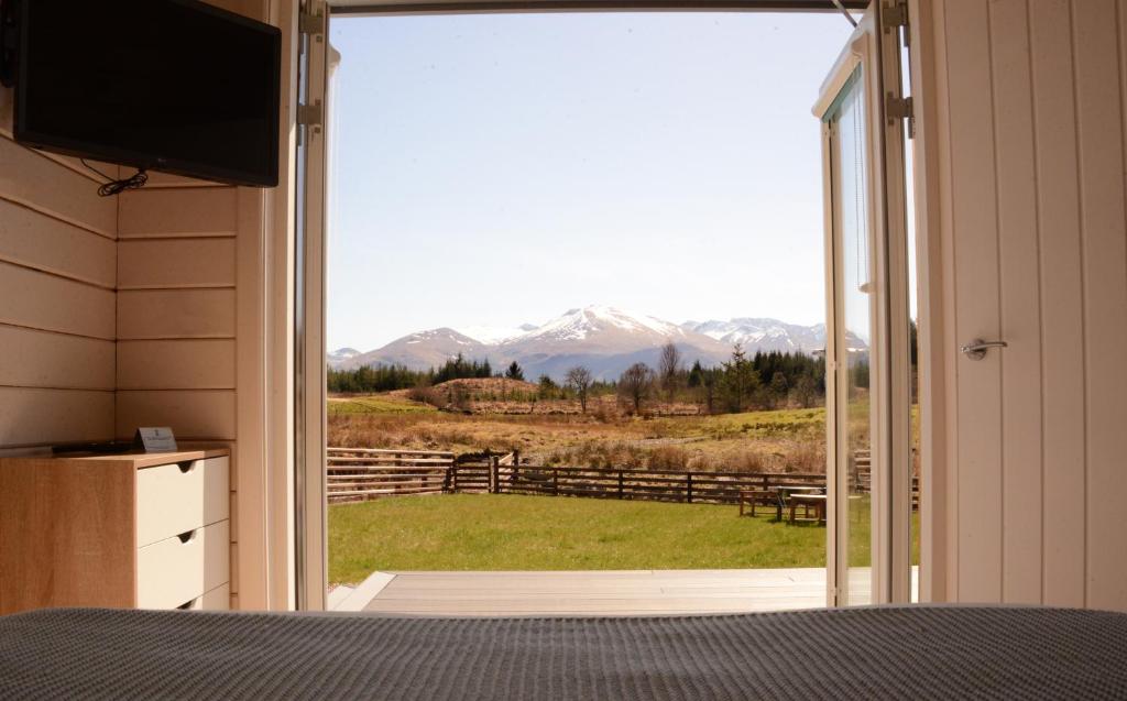 a bedroom with a view of a mountain view from a window at Toradh Cabin in Spean Bridge