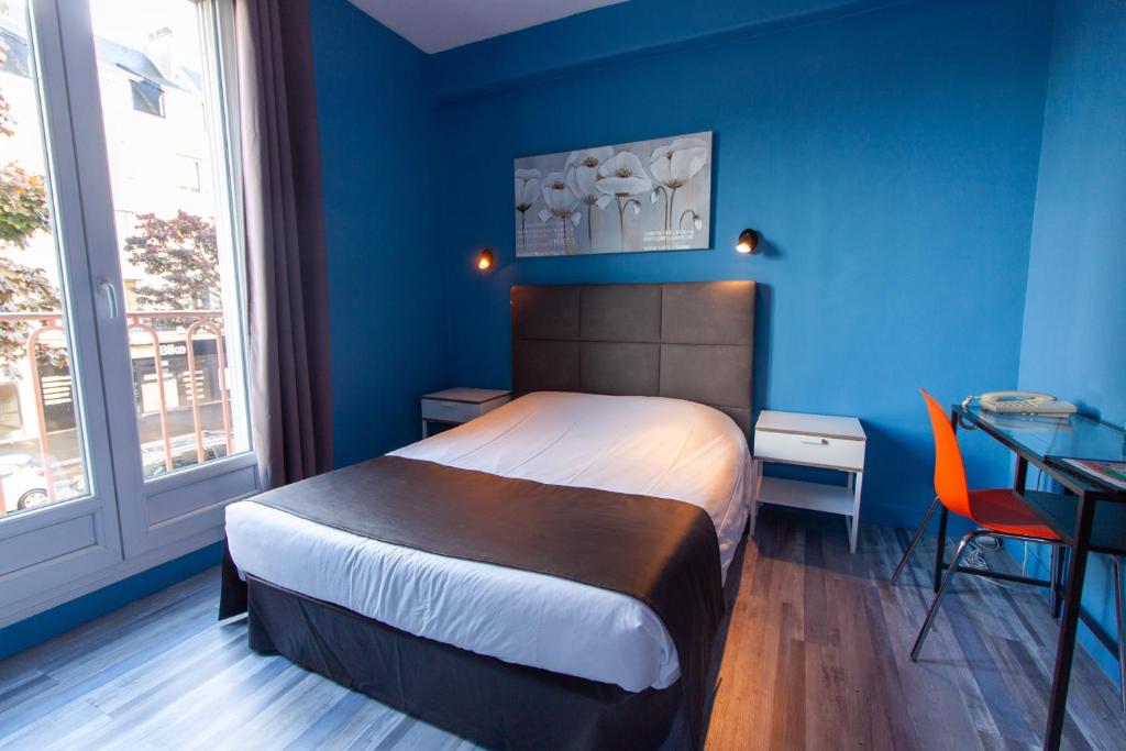 a bedroom with a bed and a blue wall at Hotel De l'Univers in Caen