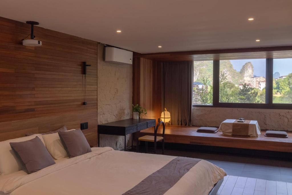 - une chambre avec un lit, un bureau et une fenêtre dans l'établissement Yangshuo Hillside Homestay, à Yangshuo