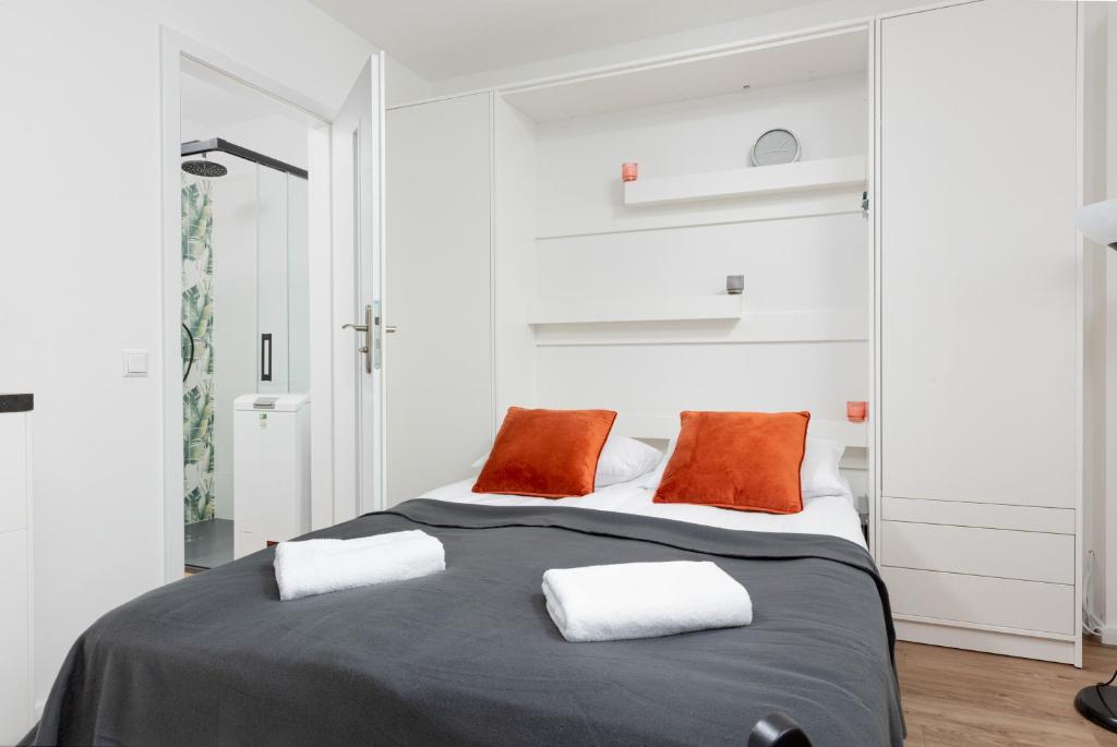 1 dormitorio con 1 cama grande y 2 almohadas de color naranja en Studio Apartment Ochota Siemieńskiego by Renters, en Varsovia