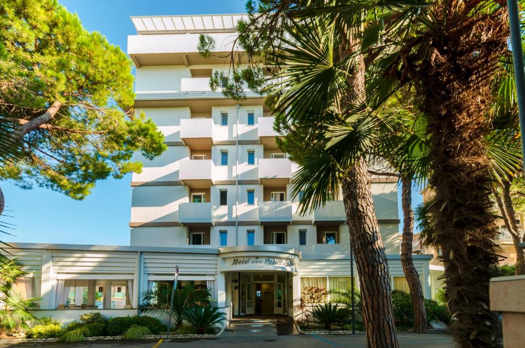 un edificio con palme di fronte ad esso di Hotel Palma de Majorca a Bibione