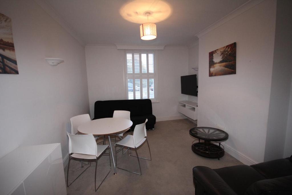 a living room with a table and white chairs at Hillingdon Hill Court, Uxbridge in Hillingdon
