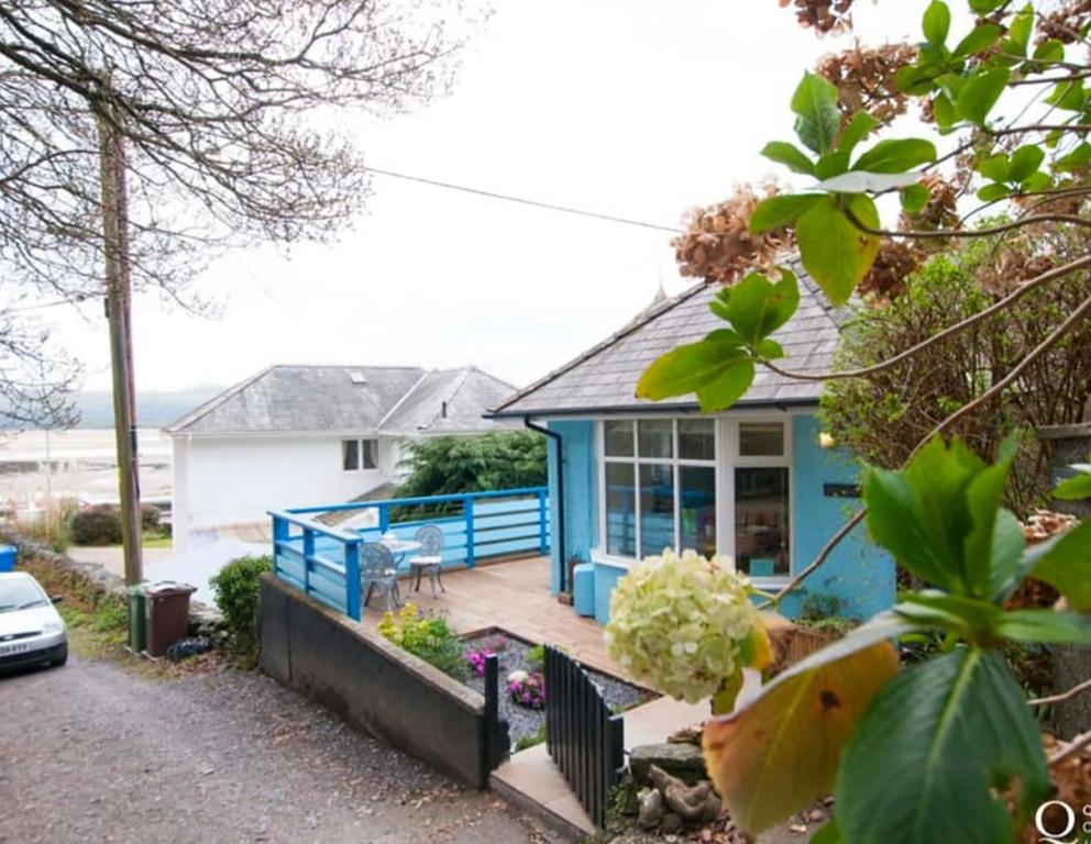 a blue house with a porch and a driveway at Kindly Light Beach House in Porthmadog
