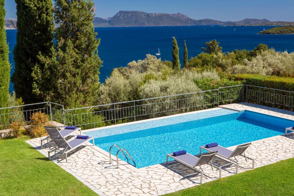 basen z krzesłami i widokiem na wodę w obiekcie Ionian Luxury Villas w mieście Nikiana