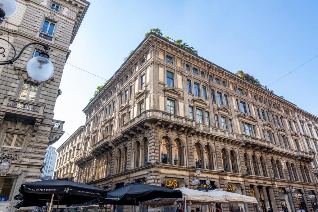 un gran edificio con sombrillas delante en Imperiale Suites Milano, en Milán