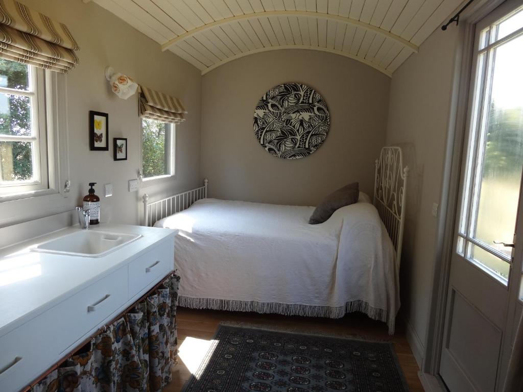 a bedroom with a bed and a sink and windows at The Oaks Glamping - Rubie's Shepherds Hut in Colkirk