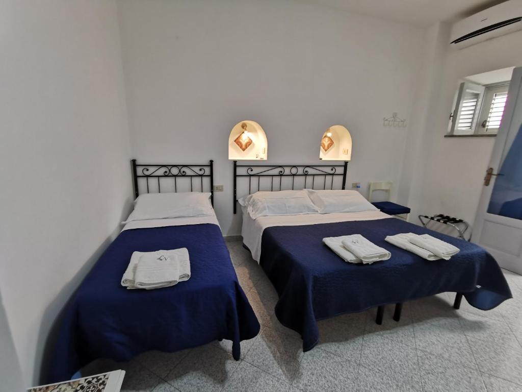 two beds in a bedroom with blue sheets and towels at Lo Nardo Accommodation in Lipari