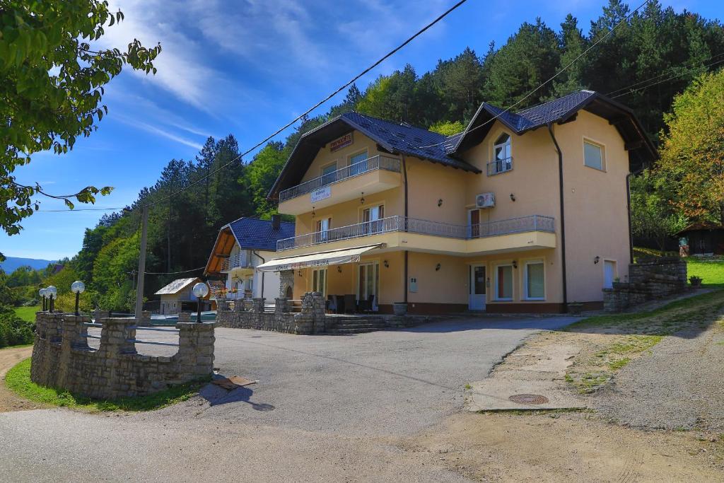 a large yellow house with a blue roof at Apartments Crvena Jabuka in Ključ