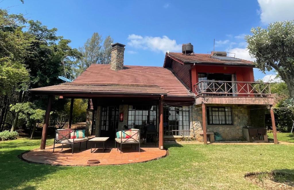 an old house with two chairs and a porch at Francolin Cottage at Great Rift Valley Lodge & Golf Resort Naivasha in Naivasha