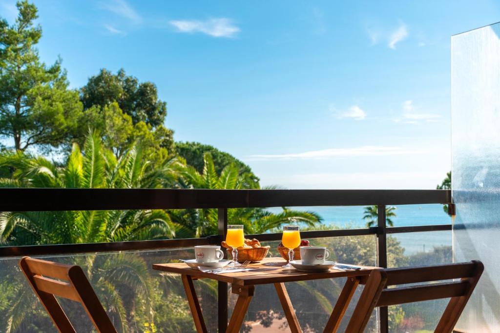 a table with two chairs on a balcony with a view at Hôtel Bahia in Villeneuve-Loubet