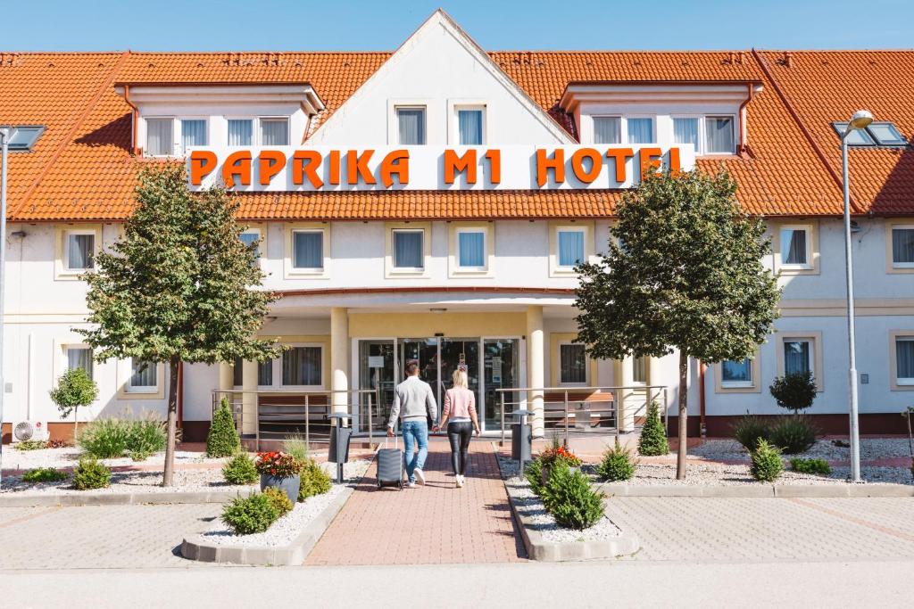 two people walking in front of a hotel at Paprika M1 Hotel in Hegyeshalom