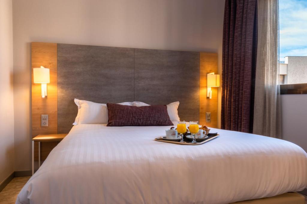 Una habitación de hotel con una cama con una bandeja de comida encima. en Hôtel Bahia, en Villeneuve-Loubet
