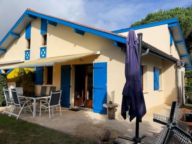 Casa azul y blanca con mesa y sombrilla en Village Océlandes, en Saint-Julien-en-Born