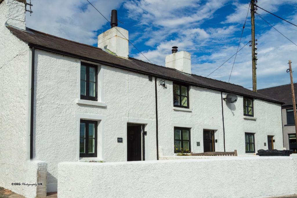 a white house with a black roof at Red Robin Cottage in Gaerwen