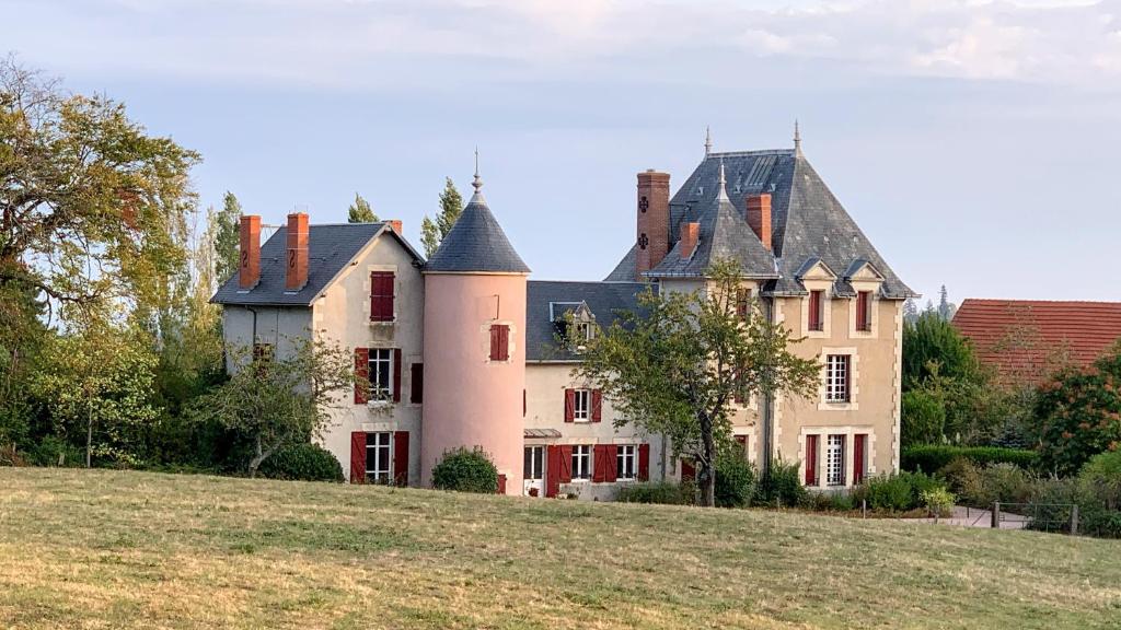 una casa grande en la cima de una colina con césped en Château de la Combe, en La Celle