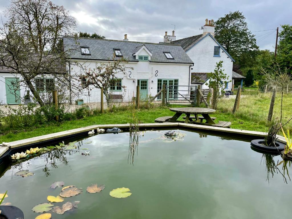a pool of water with a picnic table in front of a house at Cottages at Woodlands, Appleloft in Wareham