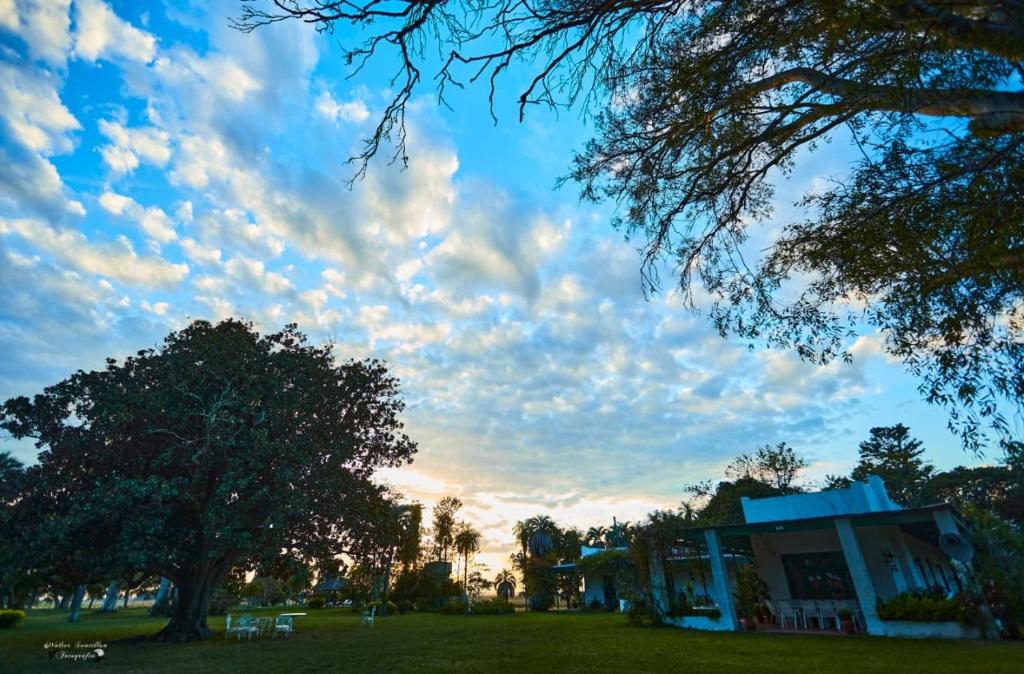 un cielo nublado sobre un parque con árboles y un edificio en Estancia Buena Vista en Esquina