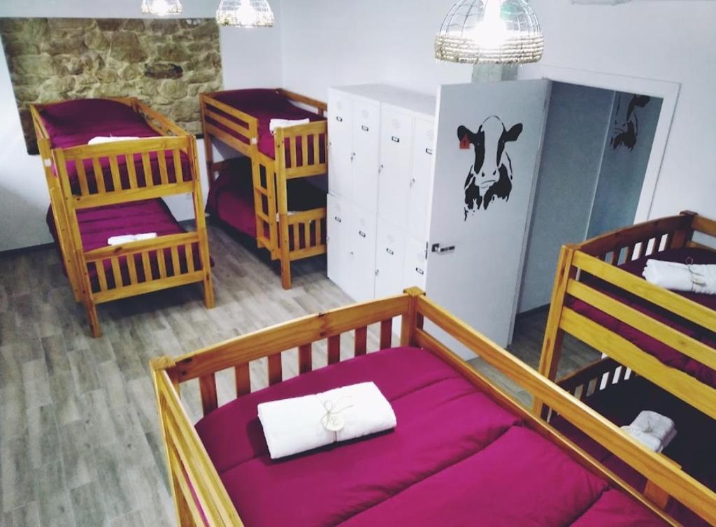 a room with three bunk beds and a refrigerator at Albergue Casa Vacas in Carriazo
